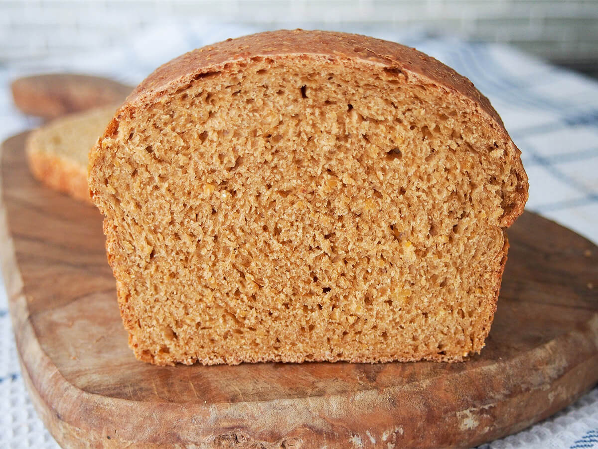 Anadama bread is a classic New England yeast bread made with molasses and cornmeal. It's gently sweet, relatively dense but tender and with a lovely rounded flavor. It's great for sandwiches, snacking and more. end on view of anadama bread on wooden board