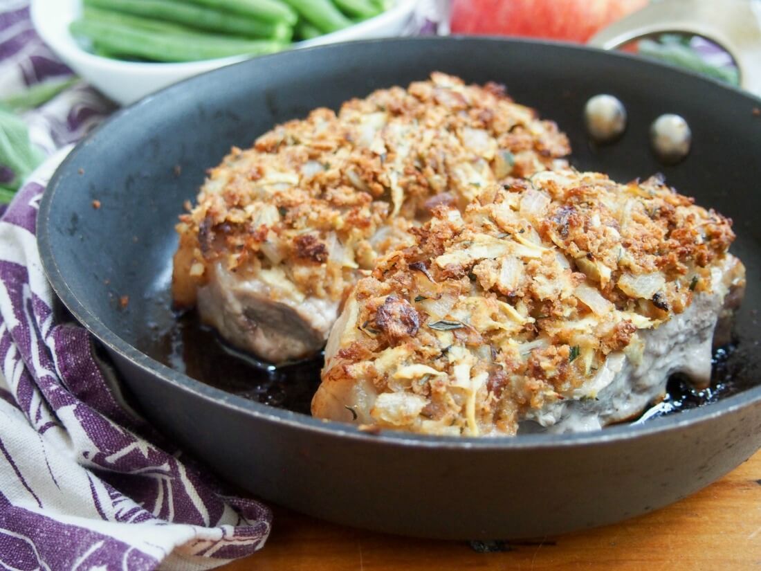 These apple stuffing crusted pork chops are easy to make and full of fall flavors. Comforting, flavorful and a great main for any night of the week. two apple stuffing crusted pork chops in skillet