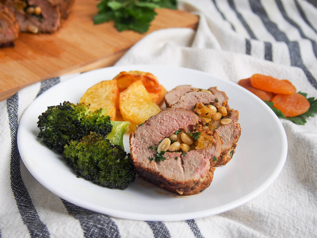 This apricot stuffed pork tenderloin has an aromatic spice rub on the outside and a simple apricot, pine nut and parsley filling. The meat is tender and delicately flavored, and the whole dish is elegant and delicious. apricot stuffed pork tenderloin with broccoli and potatoes on plate