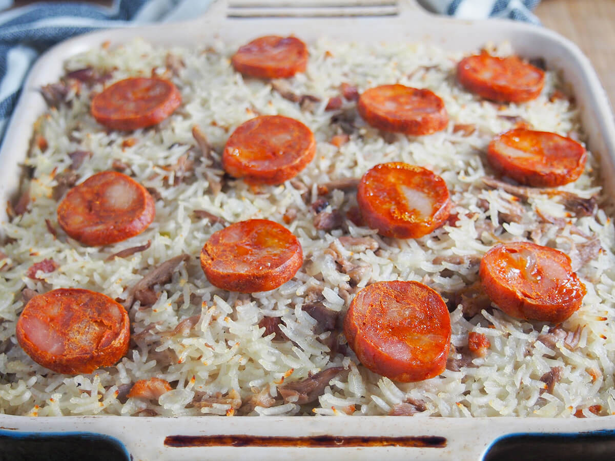 arroz de pato in dish dish of arroz de pato Portuguese duck rice with slices of chorico over top.
