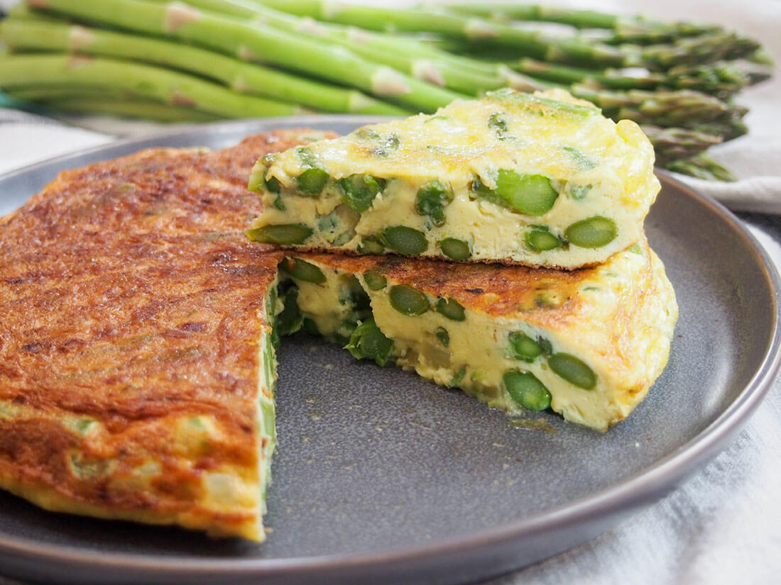This asparagus frittata is easy to make and the kind of dish that's as good at breakfast as lunch or dinner. With simple flavors, it's both fresh and comforting asparagus frittata with slice sitting on top of rest of frittata