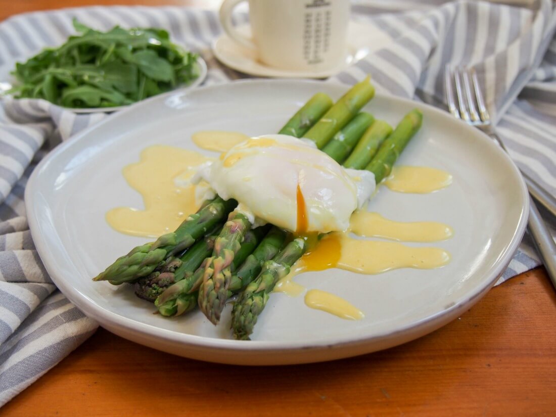 Asparagus with easy blender hollandaise sauce is an easy and delicious combination Asparagus with poached egg on top and Hollandaise sauce drizzled over with fork to side of plate