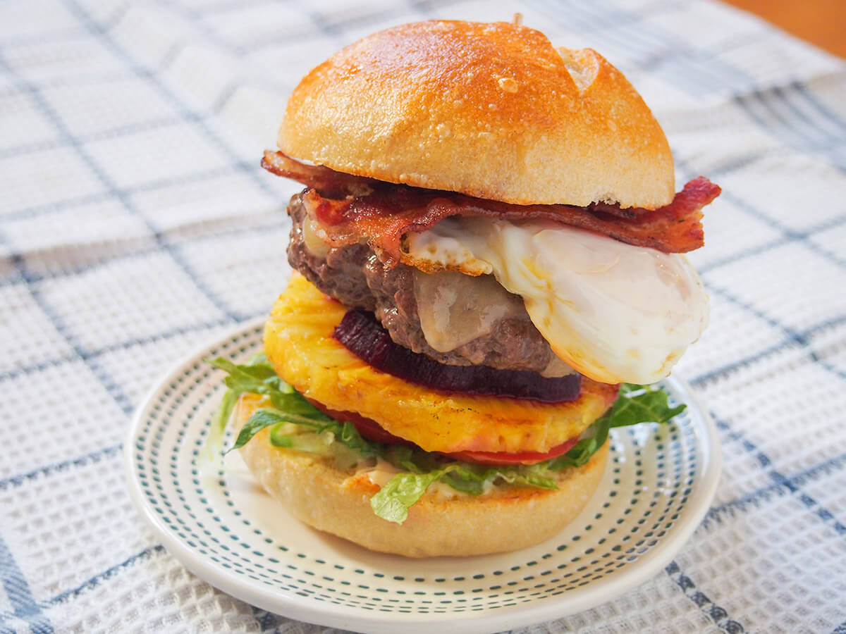 Aussie burger with the lot Aussie burger on plate on a white checked cloth