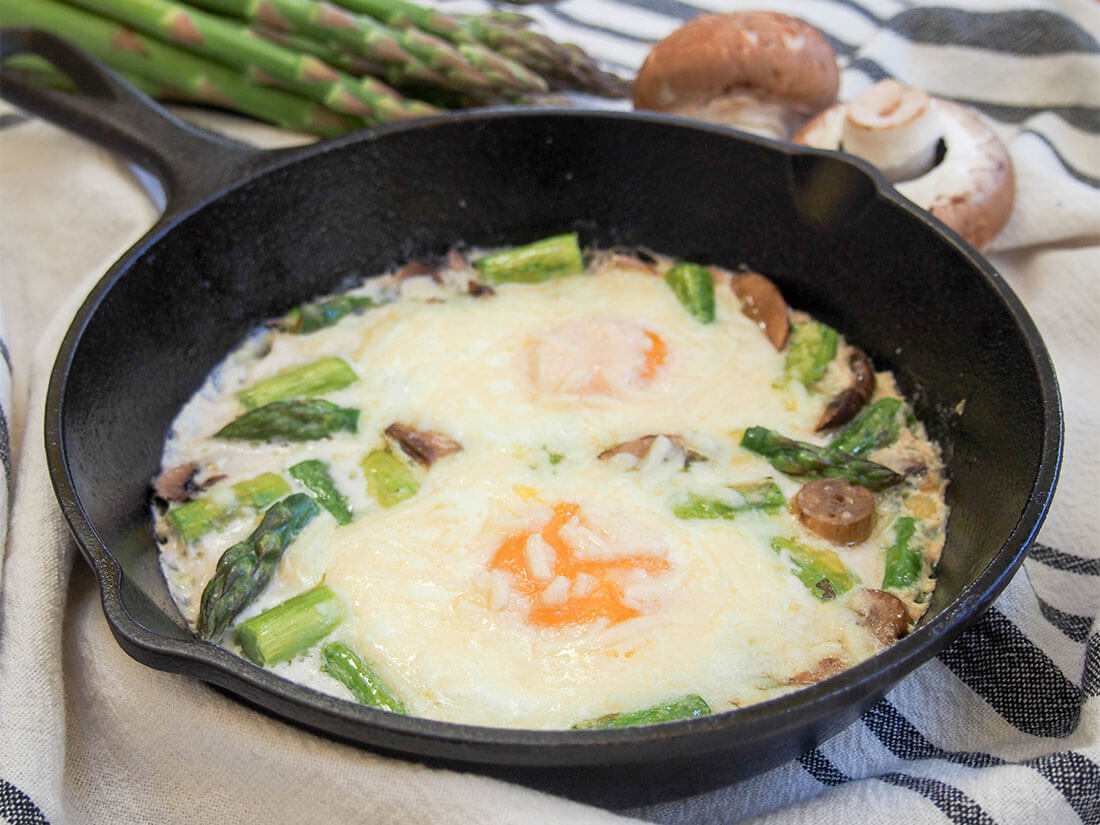 These baked eggs with mushrooms and asparagus are a deliciously comforting and easy one dish brunch. With a tasty combination of earthy and fresh flavors, it's one you'll come back to again and again. Baked eggs with mushrooms and asparagus in skillet with asparagus and mushroom behind