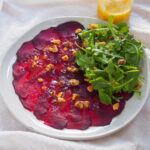 plate of beet carpaccio with jar of dressing behind