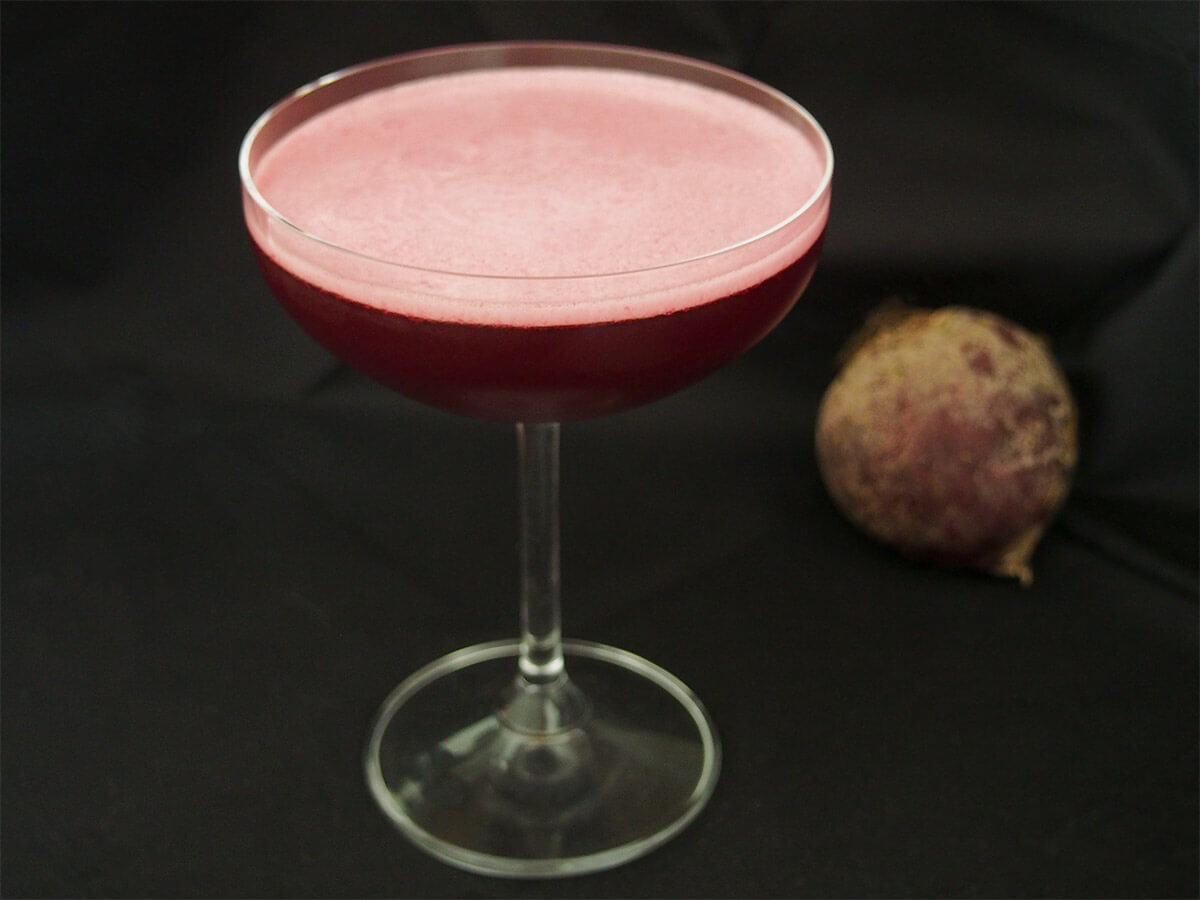 beet negroni sour - a Halloween cocktail glass of beet negroni sour Halloween cocktail with beet in background