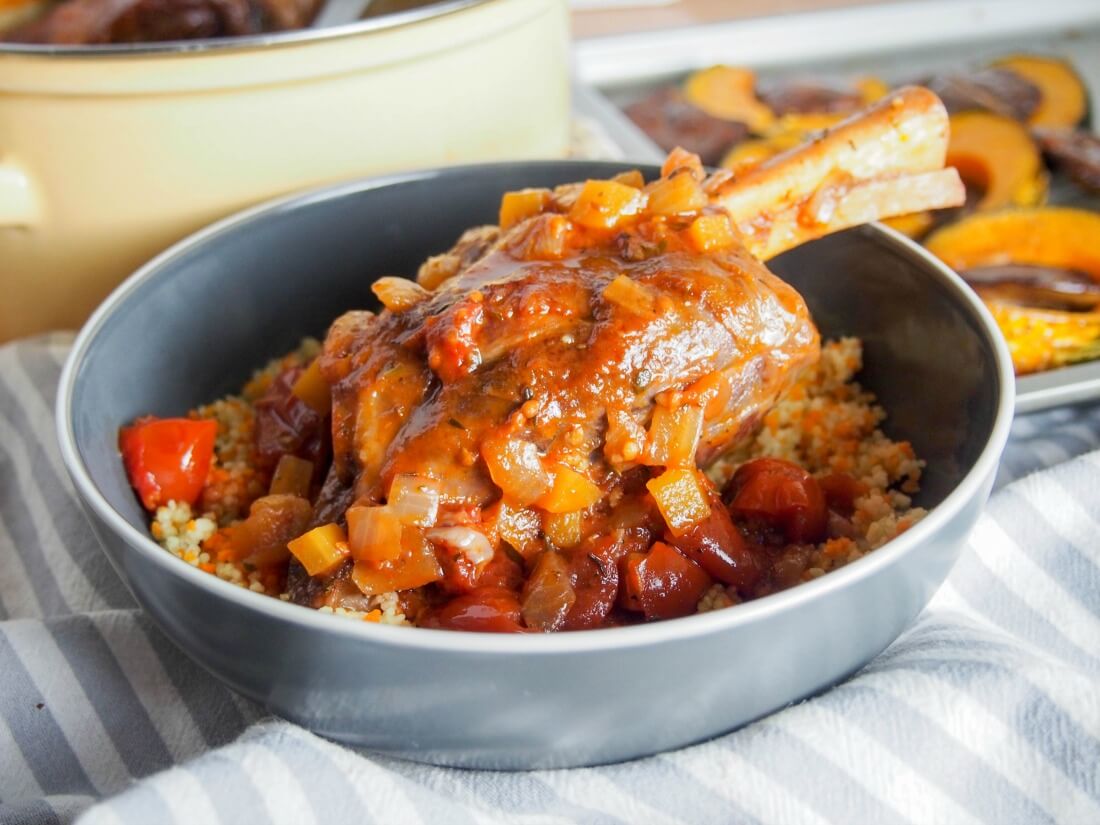 You need to be a little patient to enjoy these braised lamb shanks, but they're easy to prepare and so worth the wait. Rich, tender and delicious. The meat is tender and the sauce is so full of flavor. Comfort food at its best. braised lamb shank in bowl with sauce over top and pot it was cooked in behind