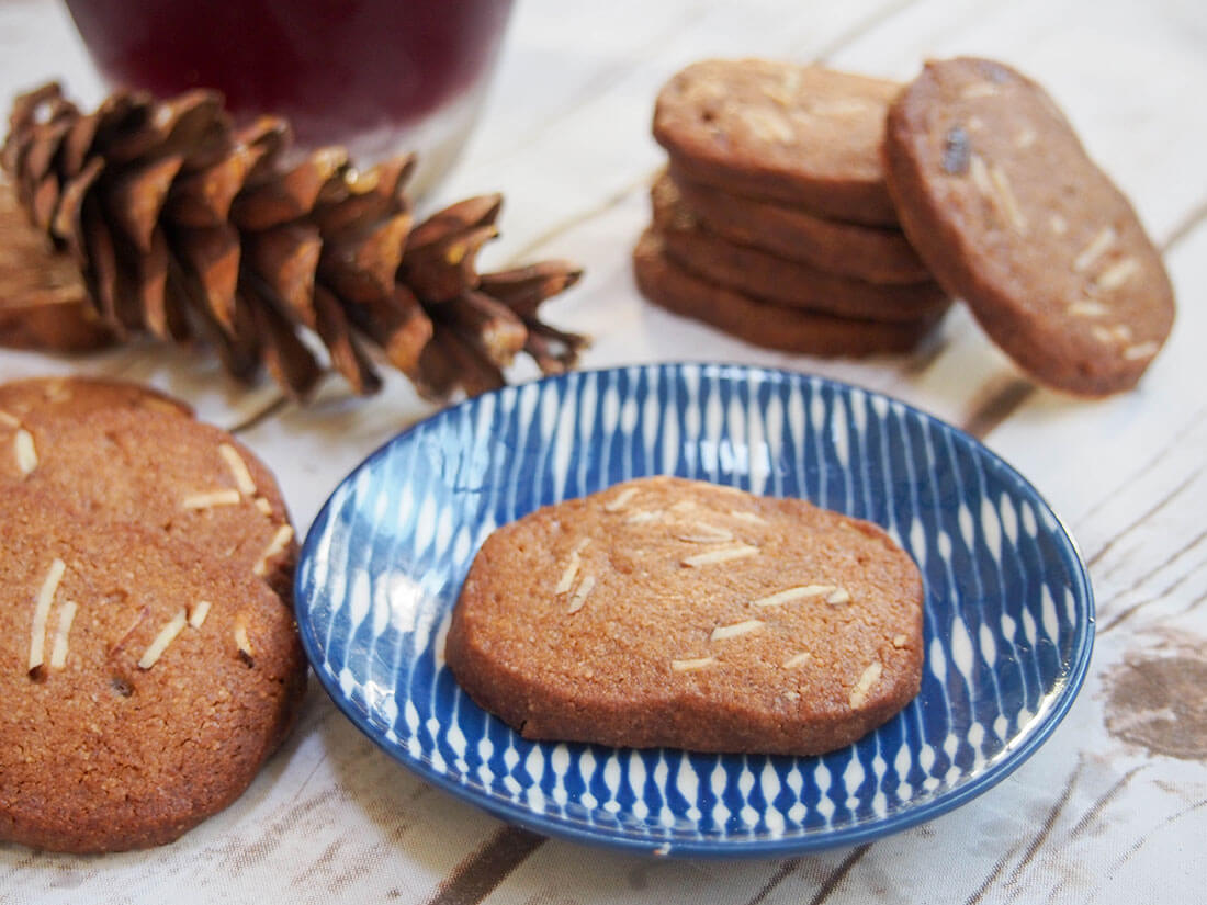 Brunkager are Danish Christmas cookies with a delicious spiced flavor and a wonderful crunch. Perfect to add to your cookie plate. Brunkager cookie on small plate with stack behind and more to side
