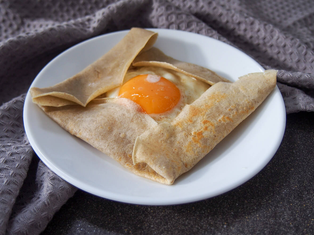These French buckwheat crepes are easy to make, naturally gluten free and with a lovely slightly nutty flavor. They're perfect loaded up with cheese, ham and egg for a classic "crêpe complete" for brunch/ lunch, or with many other tasty savory fillings. French buckwheat crepe filled with cheese ham and egg on plate