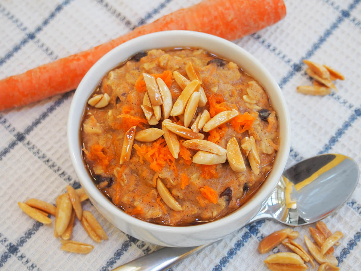 bowl of carrot cake oatmeal with spoon below bowl of carrot cake oatmeal with spoon below bowl and carrot above