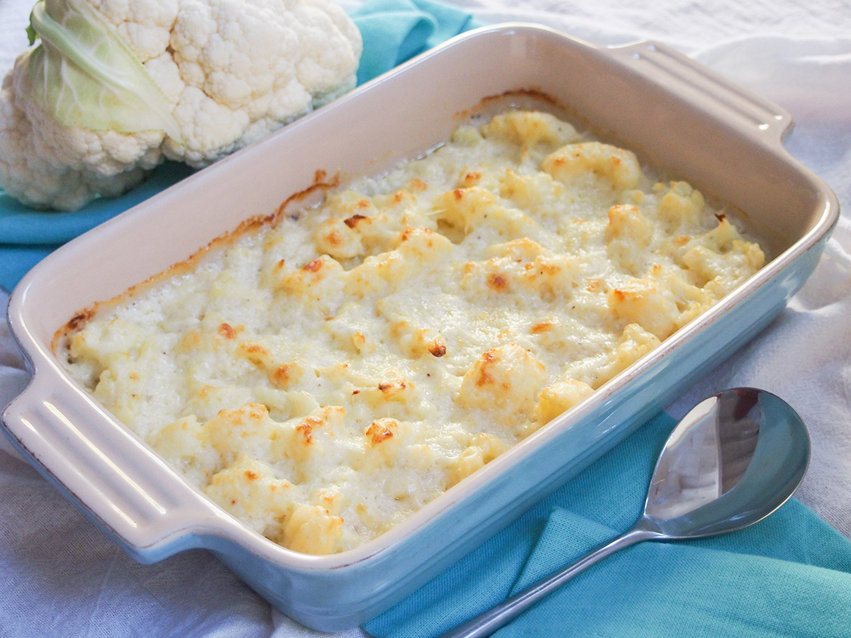 Cauliflower cheese is a classic British side dish that pairs perfectly with a roast, but also with a range of other dishes. It's easy, tasty and wonderfully comforting. dish of cauliflower cheese with serving spoon in front