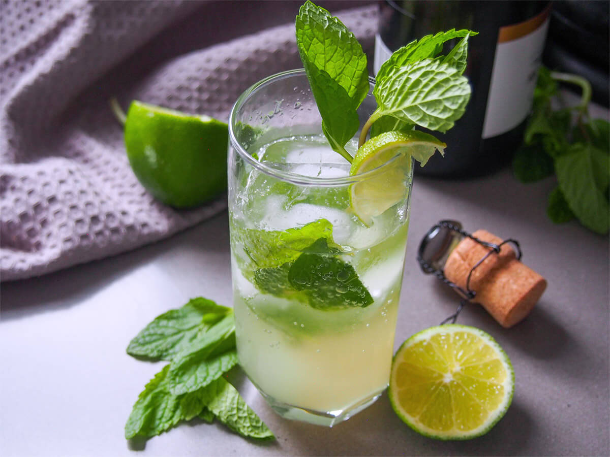 Make your cocktail that bit extra special with this champagne mojito. It has all the fresh mint and lime flavor of the original but with a lovely extra flavor from champagne as the bubbles. Perfect for a special occasion, or just because. glass of champagne mojito with lime and cork to side of glass