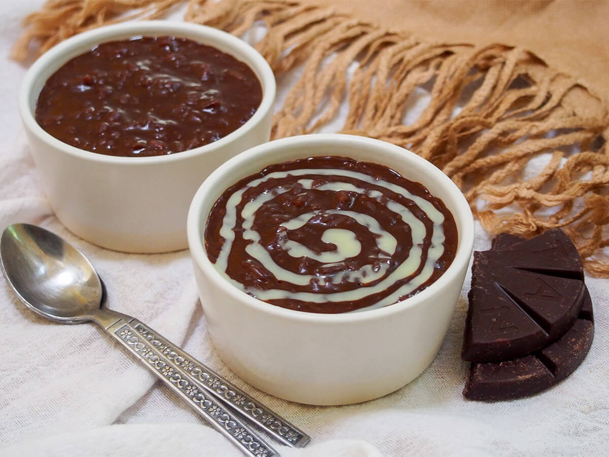 Champorado is a traditional Filipino breakfast or snack best described as chocolate rice porridge. It's easy to make, comforting, rich & smooth. two dishes of champorado with spoons to side