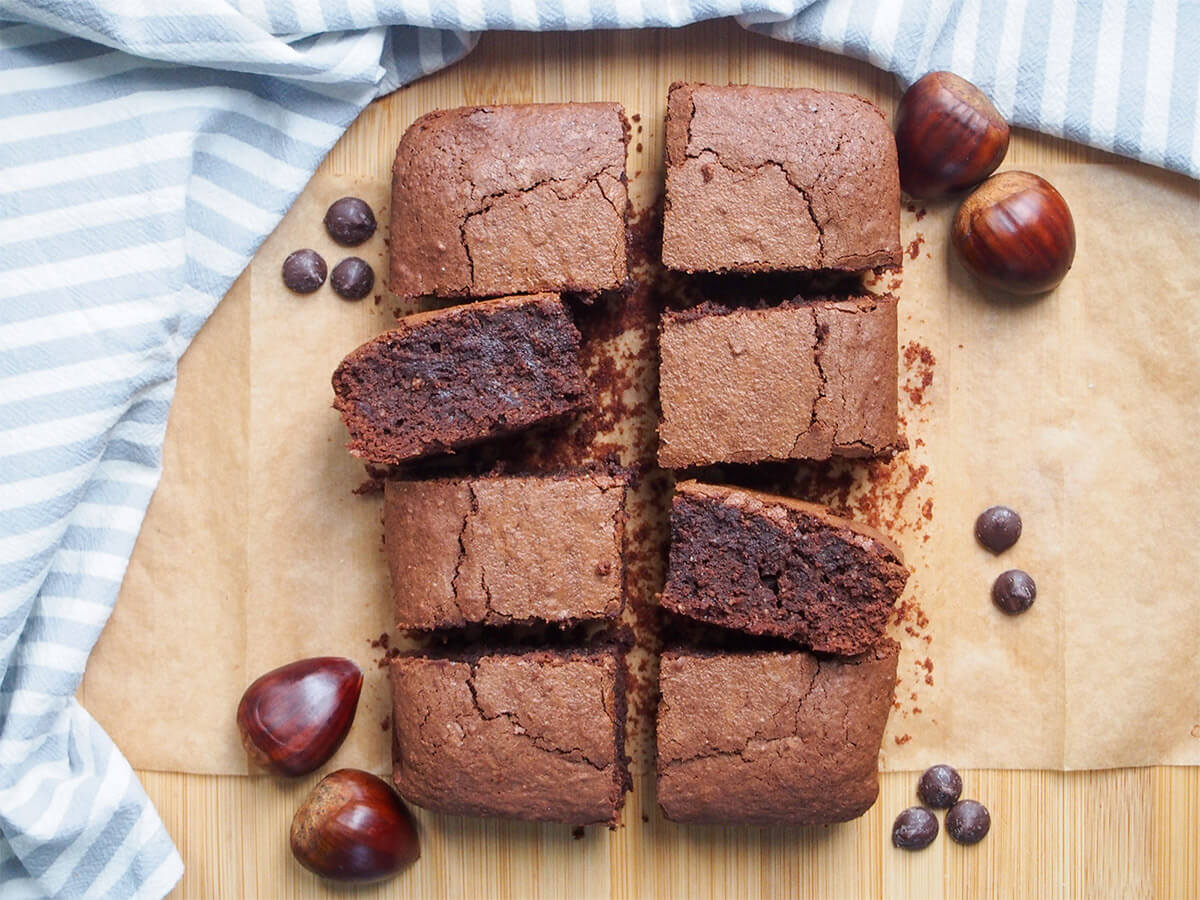These gluten free chestnut brownies are made with chestnut flour and part brown sugar, which makes them both gently nutty and wonderfully smooth, with a slight caramelized flavor too. Seriously good. rows of gluten free chestnut brownies with chestnuts to side of them