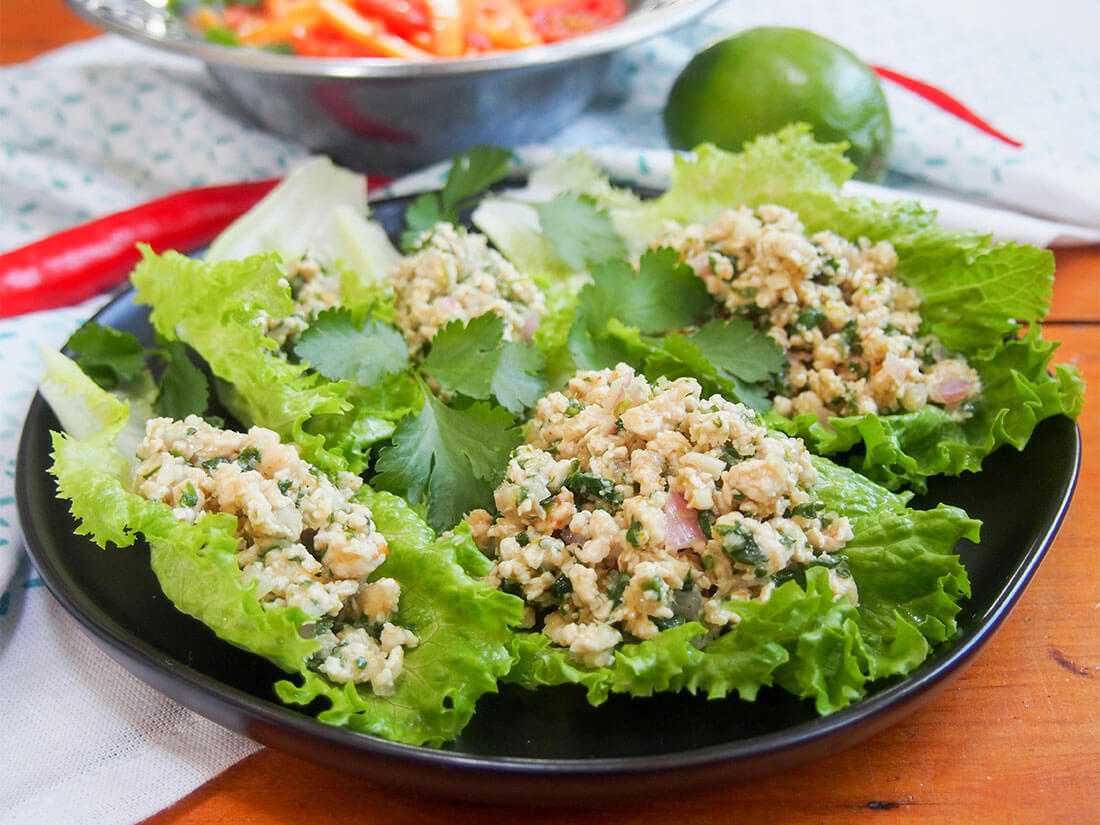 Larp (larb gai) is a classic Thai/Laos chicken salad, though unlike any chicken salad you may be familiar with. This one is packed with delicious lemongrass, lime, cilantro and chili alongside the meat itself. Healthy, light, flavorful & great for a picnic or lunchbox. plate of lettuceleaves topped with larp (larb gai, Thai/Laos chicken salad)