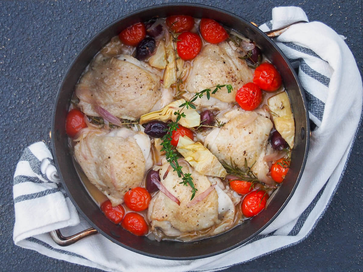 Chicken Provençal/Provencal is an easy and delicious combination of chicken, tomatoes, olives and herbs. It takes minimal preparation and is perfect for a midweek meal with rice or bread. dish with chicken provencal with cloth looped in handles of dish
