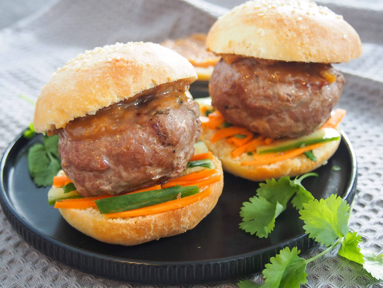These chicken satay burgers take the flavors of the classic grilled chicken dish and put them in burger form! A delicious mix of seasoned burger, punchy peanut sauce and crunchy slaw, it's all kinds of tastiness. It's great for preparing ahead, too. chicken satay burgers on plate