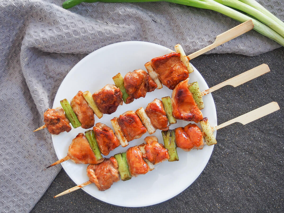 Chicken yakitori are incredibly easy Japanese chicken skewers that take no time to make with deliciously tasty results. Perfect to add to your summer grilling menu (or any time). plate of chicken yakitori from above with spring onions above plate