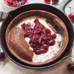 close view of chocolate Dutch baby pancake with cherry compote