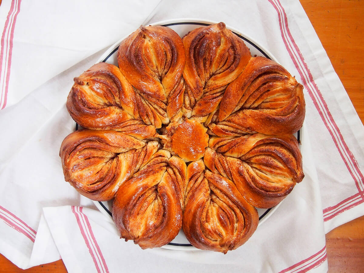 This cinnamon star bread is an impressive-looking and delicious-tasting lightly sweet bread that's perfect alongside coffee or for a festive brunch. It's soft, flavorful and easier to make than it looks. So get ready to wow. whole cinnamon star bread on plate on top of white cloth