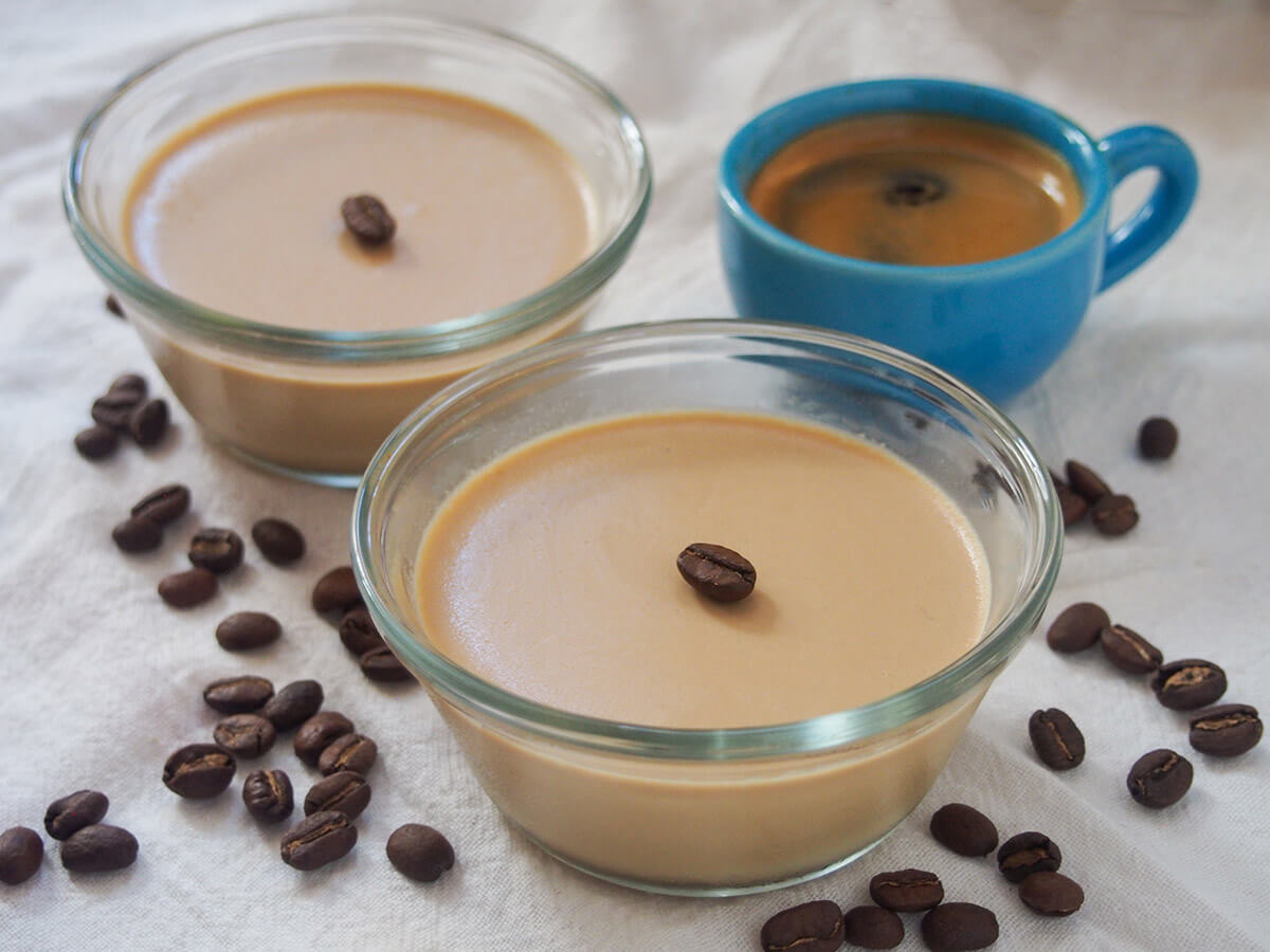 This coffee panna cotta is such a wonderfully flavored twist on the classic easy, make ahead dessert. It's creamy, with a great coffee flavor and just the right amount of sweetness. Perfect to enjoy any excuse. two dishes of coffee panna cotta with coffee beans around them