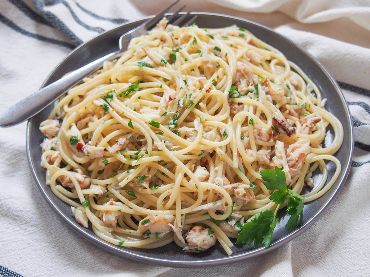Crab pasta is incredibly quick and easy, but also wonderfully fresh, delicately flavored and thoroughly delicious. A great quick meal. plate of crab pasta from side with fork at back of plate