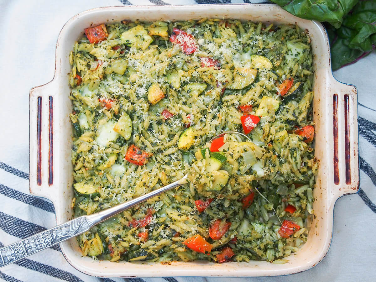 This creamy chard pesto baked orzo has all the comfort factor you would want in colder weather with that bit of freshness, too. It has plenty of gooey cheese, but lots of healthy veg as well. Perfect for any occasion. dish of creamy chard pesto baked orzo with spoonful sitting on top