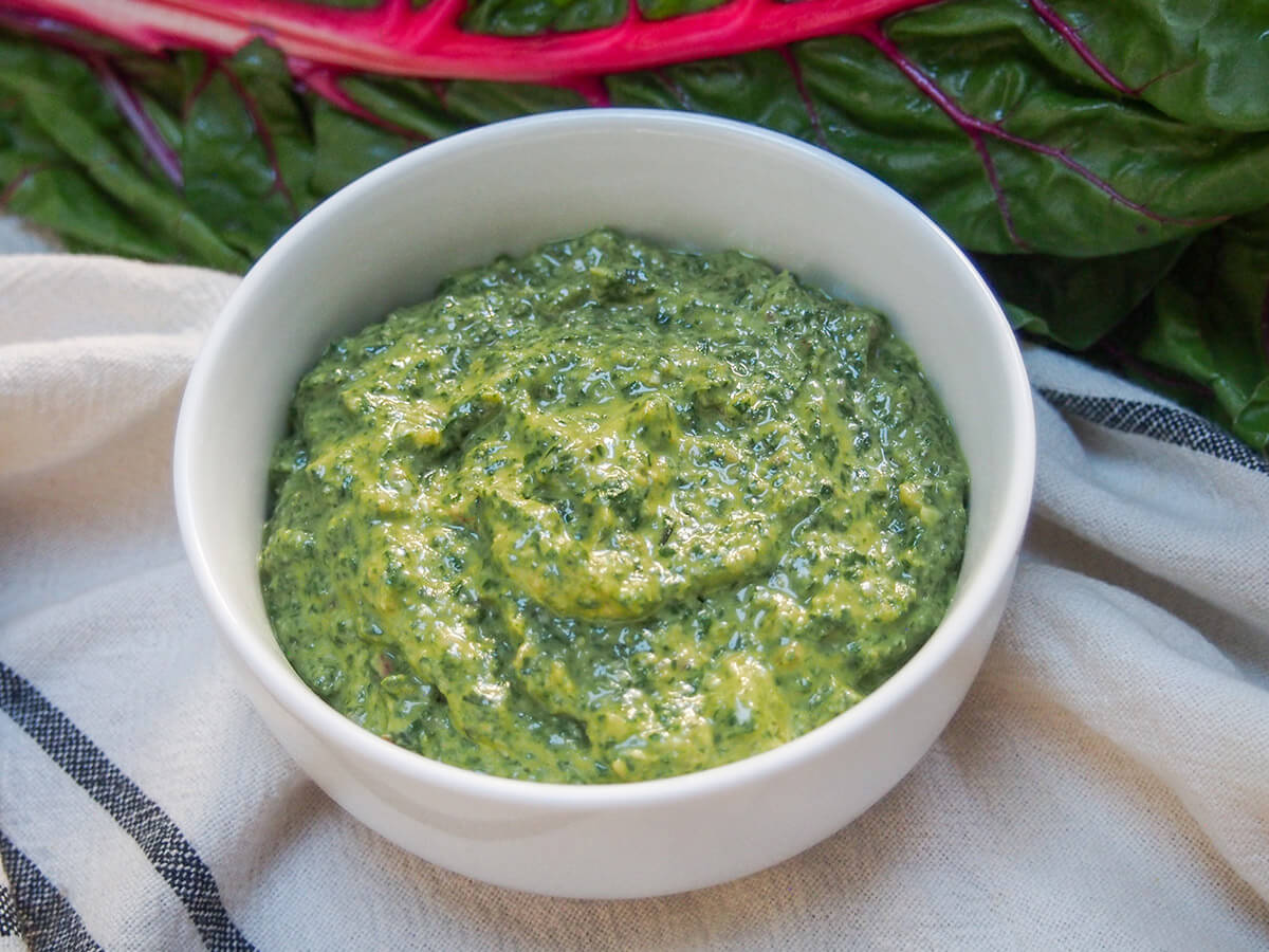 bowl of creamy chard pesto bowl of creamy chard pesto with part view of chard leaf behind