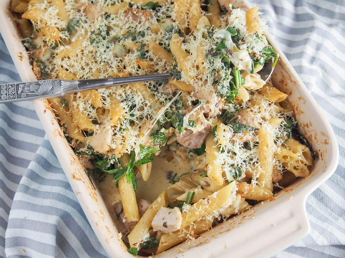 This creamy lemon chicken pasta bake has so much tastiness going on from the tarragon lemon cream sauce that wraps together the pasta, chicken and spinach. Creamy lemon chicken pasta bake in dish with spoon of pasta resting on top
