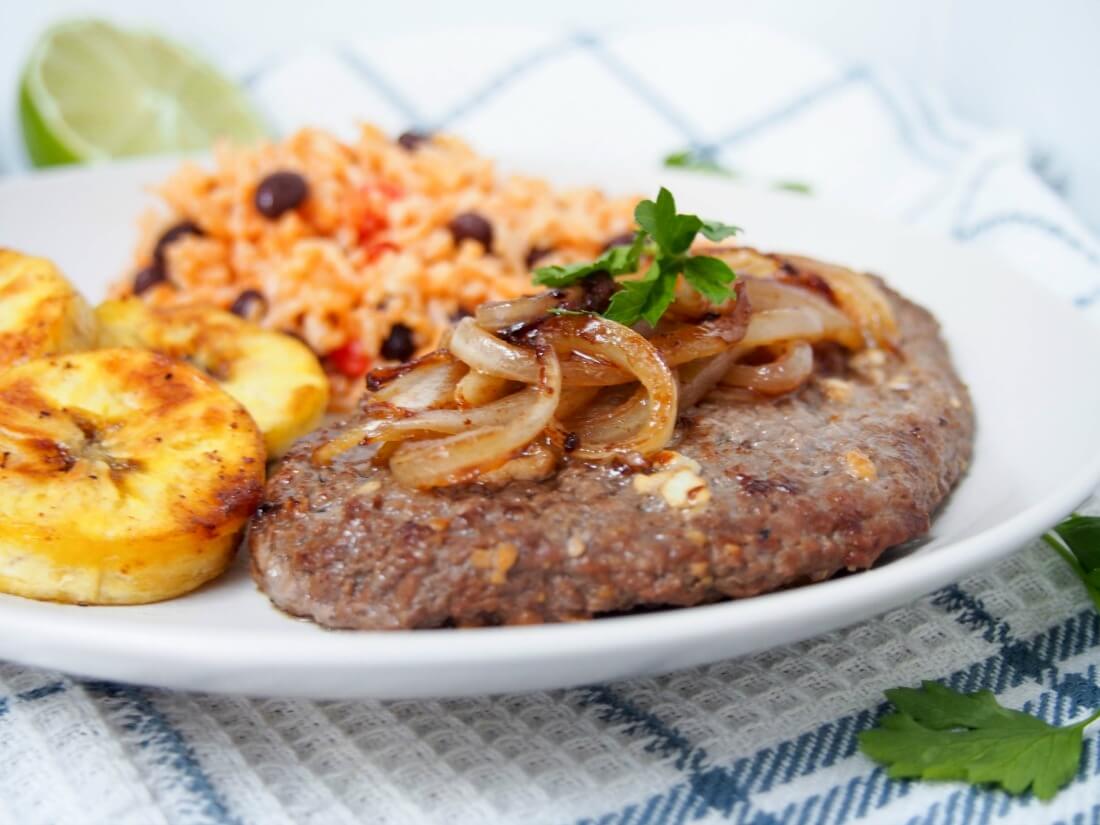 Cuban cube steak - Bistec de Palomilla is such an easy way to prepare cube steak with great results. You'll be amazed at how the simple lime and garlic marinade transforms this into a tender, flavorful main. bistec de Palomilla topped with onions with plantain slices to side