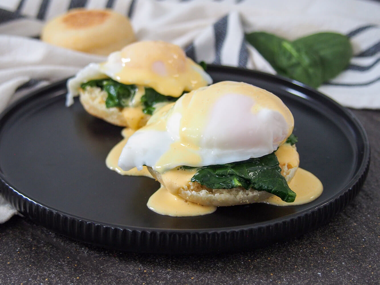Eggs Florentine is an easy and delicious vegetarian variation on Eggs Benedict. It's a great combination that's perfect for brunch. two stacks of eggs Florentine on black plate