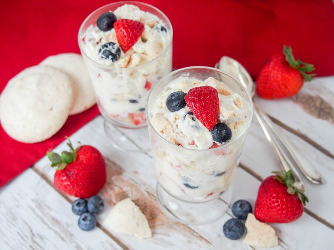 Eton mess is a classic British dessert that is incredibly easy to prepare - simply fruit, cream and meringue mixed together - but the result is so delicious. It's perfect for a party or easy anytime treat. two glasses of Eton mess with fruit and meringue to side