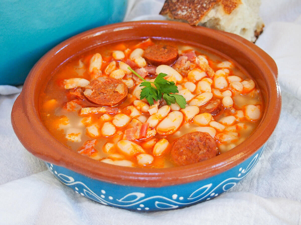 You may well have heard of cassoulet - well fabada Asturiana is it's Northern Spanish cousin. A hearty, warming white bean stew with lots of porky goodness, it's incredibly easy and perfect for a cold day. bowl of fabada asturiana with bread resting on back on bowl
