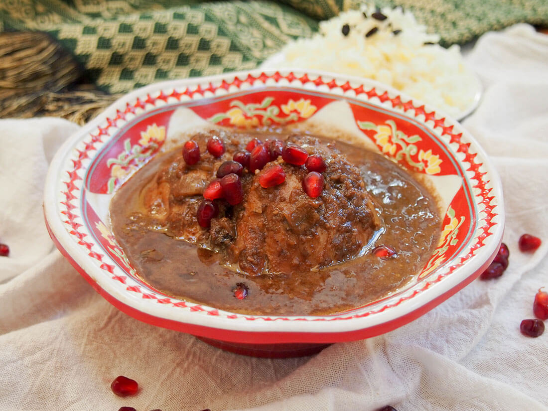 Fesenjan is an easy and delicious Persian stew. The pomegranate and walnut sauce makes it hearty and with an unusual sweet-tangy flavor. Plus, it's great to make ahead. bowl of fesenjan topped with pomegranate arils