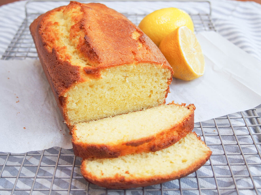This French lemon yogurt cake is so easy to make and the result is one incredibly delicious, moist, light and flavorful loaf that works for so many occasions. French lemon yogurt cake with two slices cut from loaf falling forward