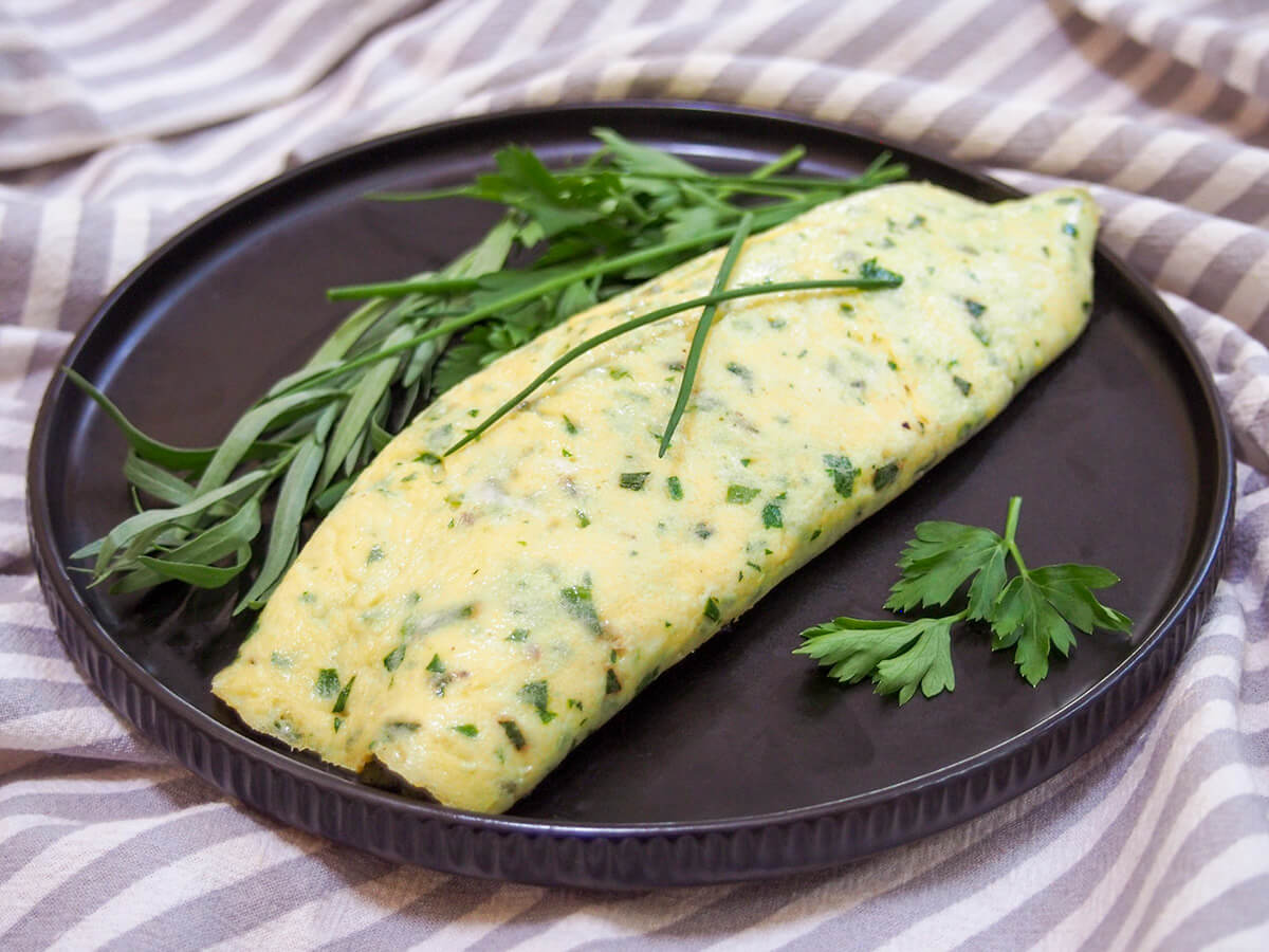A traditional French omelette (omelet) is light, simple and oh so tasty. This version with a delicate herb filling makes a delicious and easy breakfast (though it's great any time of day). French omelette with herbs on plate