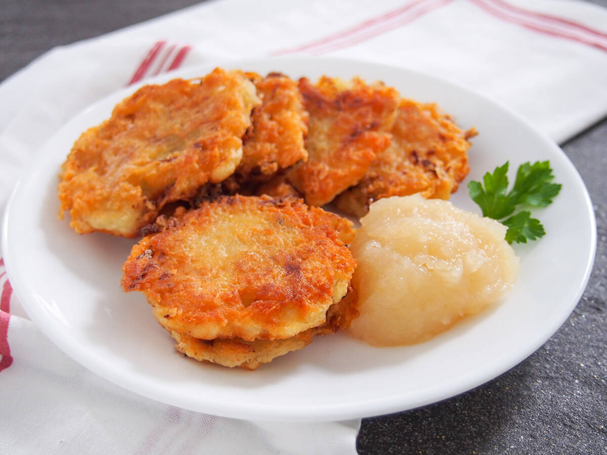 German potato pancakes are really easy to make with a crisp outside and soft inside. They're a traditional snack or side for Oktoberfest, but also great any time. plate of German potato pancakes with apple sauce on side of plate