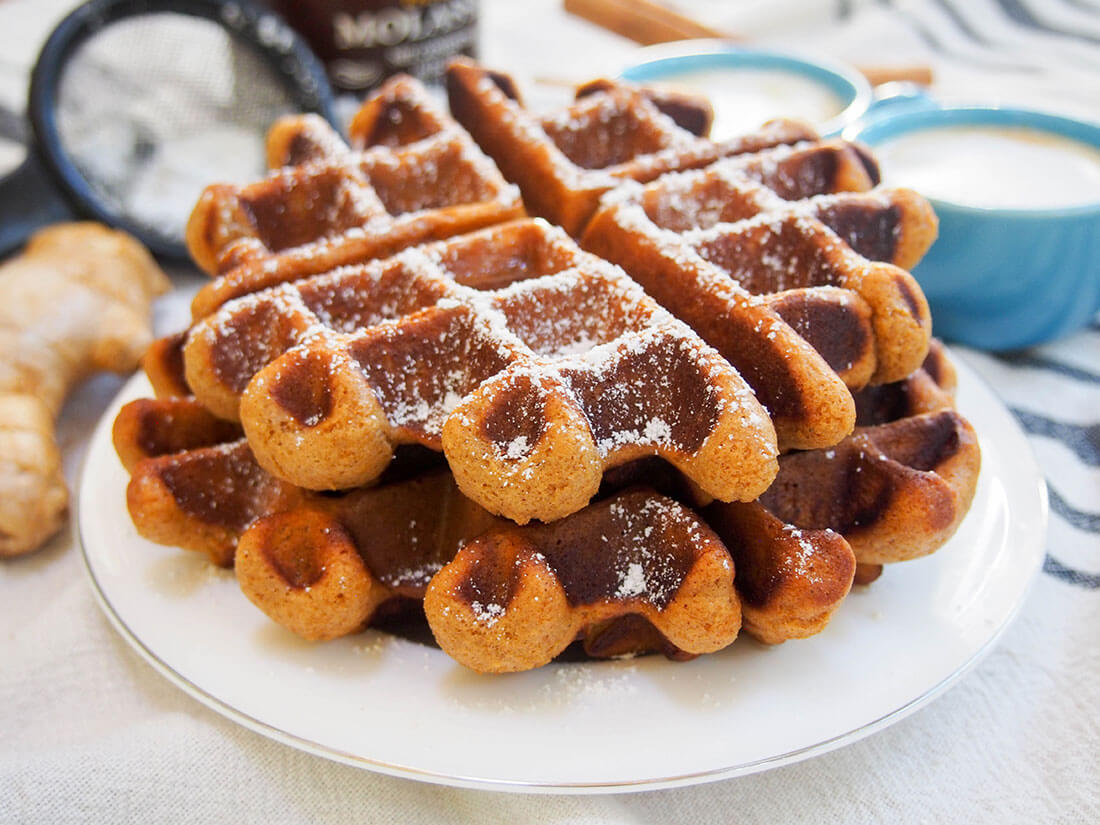 These gingerbread waffles tease you with they wonderfully warm spice smell as they cook and are just as tasty when you, thankfully, get to eat them soon after. An easy and delicious breakfast! two gingerbread waffles stacked on top of each other on plate
