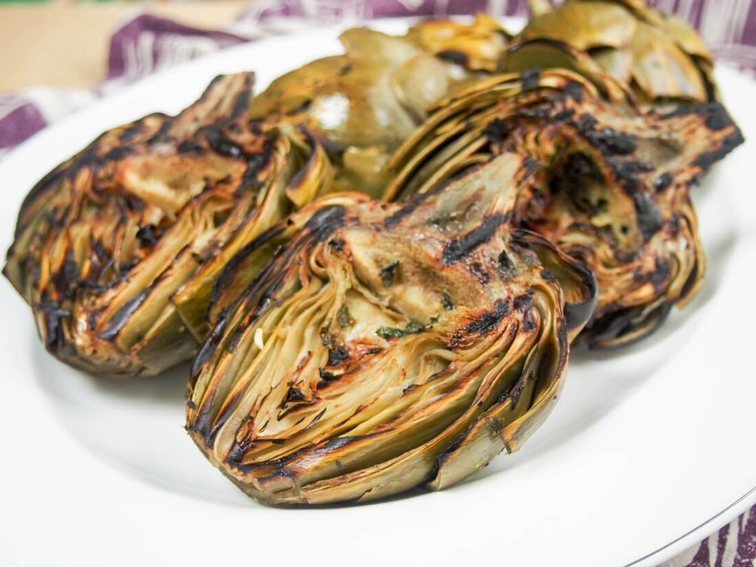 Artichokes may seem a little fiddly, but they are so worth the effort, especially when they taste as good as these grilled artichokes. The grilling flavor and garlic-herb oil makes all the difference. A great appetizer. plate of grilled artichokes from side