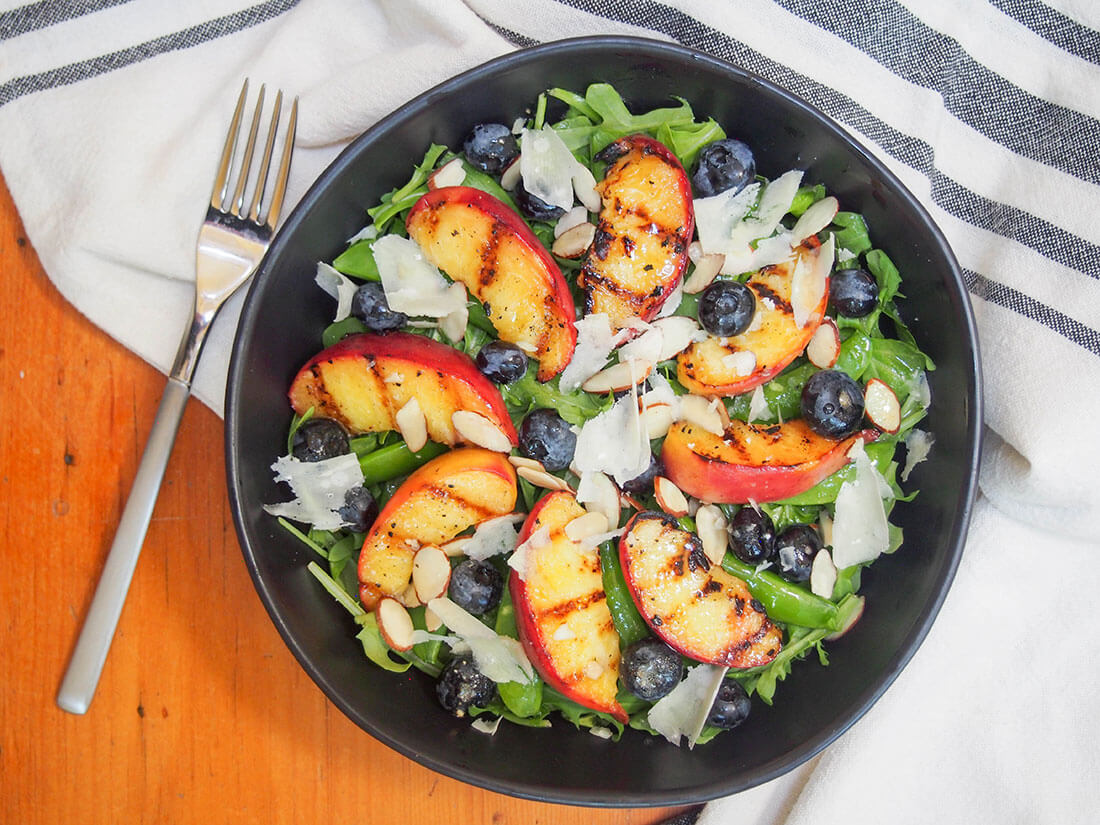 This grilled peach salad has a little sweet, a little savory, tender fruit and crunchy veg. A delicious, light and easy summer salad. grilled peach salad in bowl with fork to side