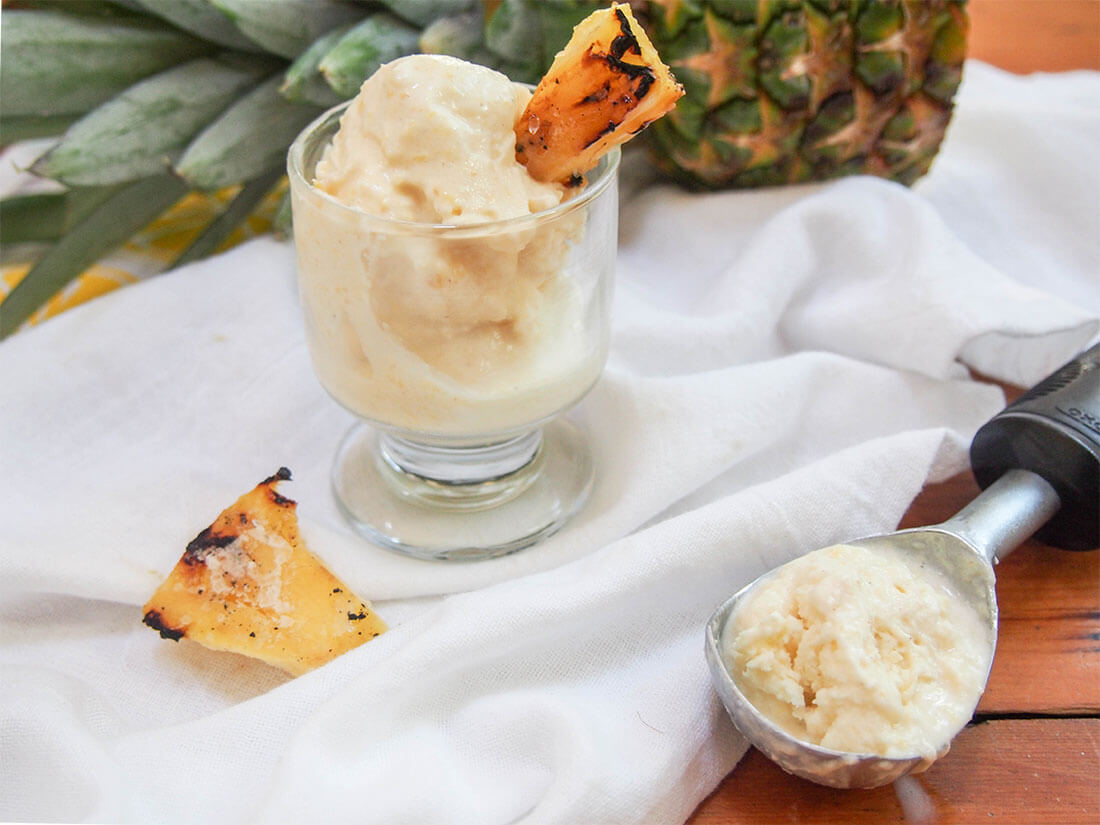 This grilled pineapple ice cream is easy to make and deliciously fresh and creamy. Gently pineapple-flavored, it's perfect to enjoy on a warm day. grilled pineapple ice cream in glass with scoop to side