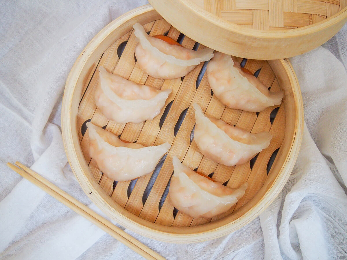 har gow, crystal shrimp dumplings har gow crystal shrimp dumplings in steamer basket form overhead with chopsticks below.