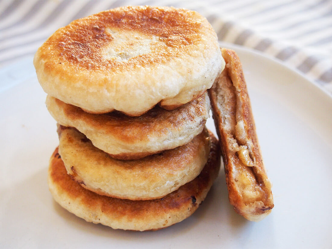 Hotteok are Korean sweet pancakes made with a yeasted dough and sweet nut filling. They're a classic street food, especially in winter, and make a delicious anytime treat. hotteok Korean sweet pancakes in stack with one bitten to side