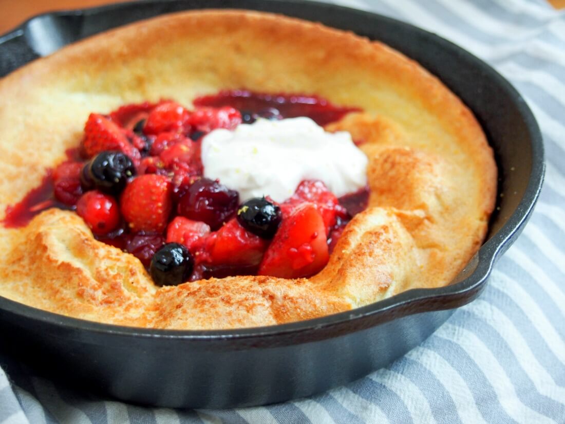 individual Dutch baby pancake with berries and maple yogurt individual Dutch baby pancake in skillet topped with berries and maple yogurt