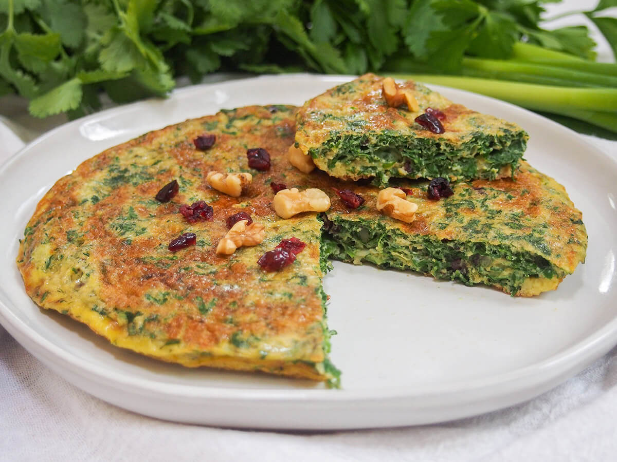 Kuku sabzi - Persian herb frittata plate with kuku sabzi Persian herb frittata with slice on top of rest