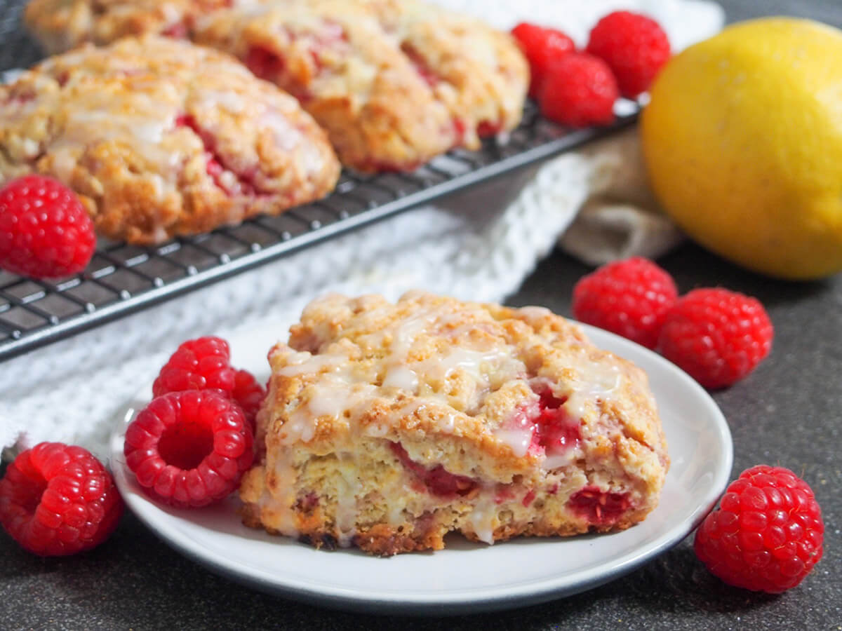 raspberry scones raspberry scone on plate with raspberries around, lemon and more scones behind
