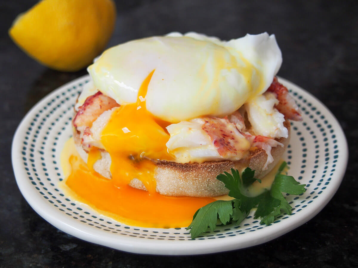 If you're wondering what to make for a special brunch, this delicious lobster eggs Benedict is the perfect choice. Wonderful delicate flavors, it's somewhat decadent but entirely worth it. And even better, it's easy to make too. lobster eggs Benedict on plate with yolk running into sauce