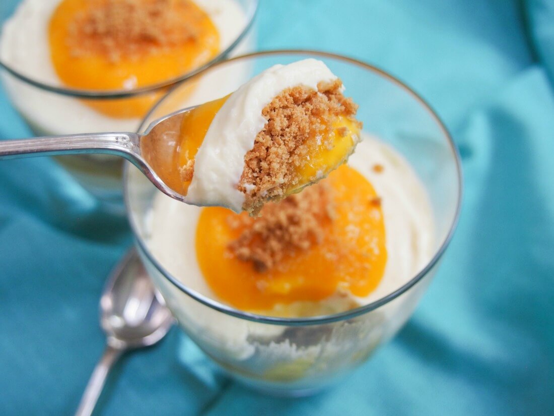 mango cheesecake parfait - an easy and delicious no bake dessert mango cheesecake parfait with spoonful held over glass