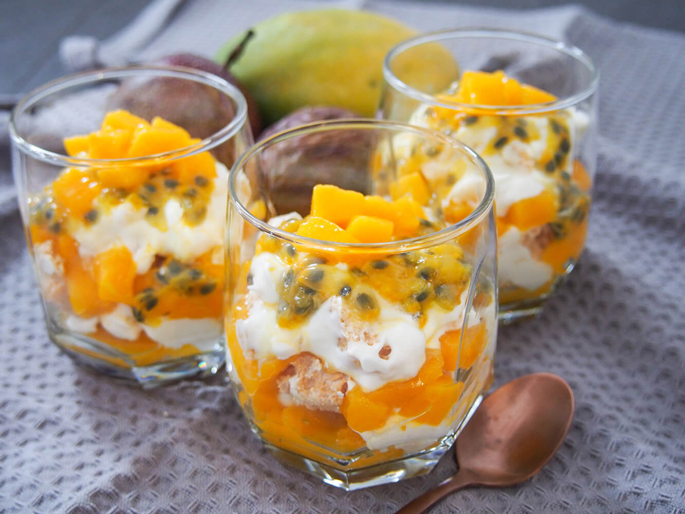 This mango passion fruit Eton mess is a wonderfully tropical and luscious twist on the classic British dessert. It's incredibly easy to prepare, being just cream, fruit and meringue, and tastes both light and indulgent at the same time. three glasses of mango passion fruit Eton mess