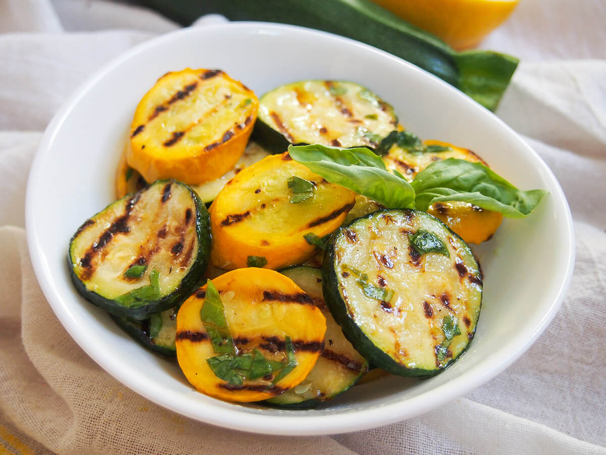 Whether you eat them straight away, or pack them for a picnic, these lemon and basil marinated zucchini and summer squash make a delicious, easy side dish. bowl of marinated grilled zucchini and summer squash with basil garnish